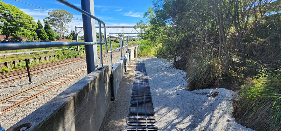 Large 500mm wide cast iron drain installed alongside a wall next to a train track